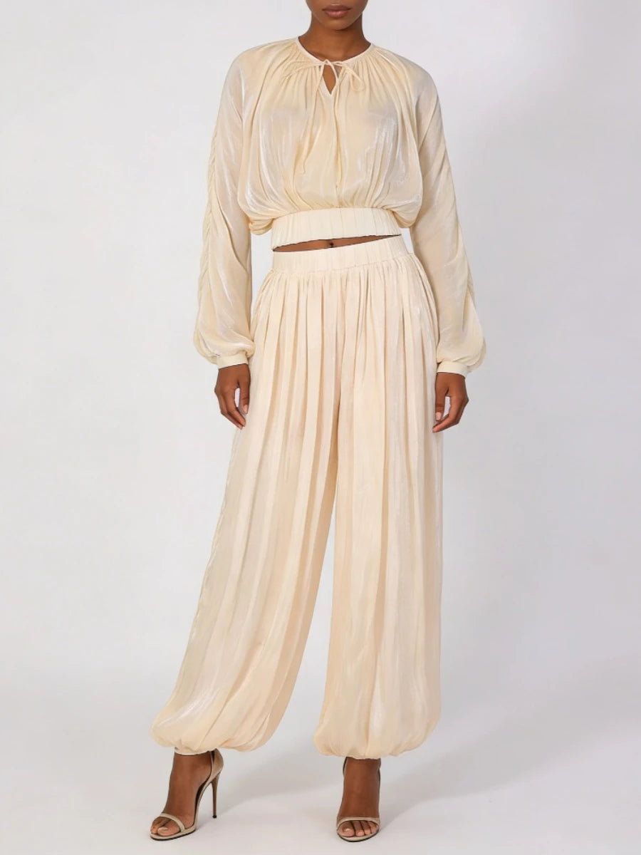 Woman wearing a beige outfit with a top and wide-leg pants on a white background