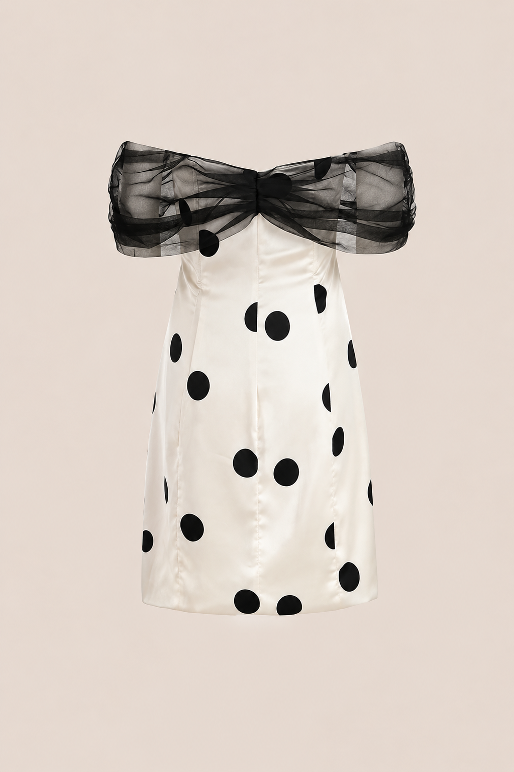 An off-the-shoulder white dress with black polka dots and a sheer black tulle bow at the neckline, shown against a solid pale beige background.